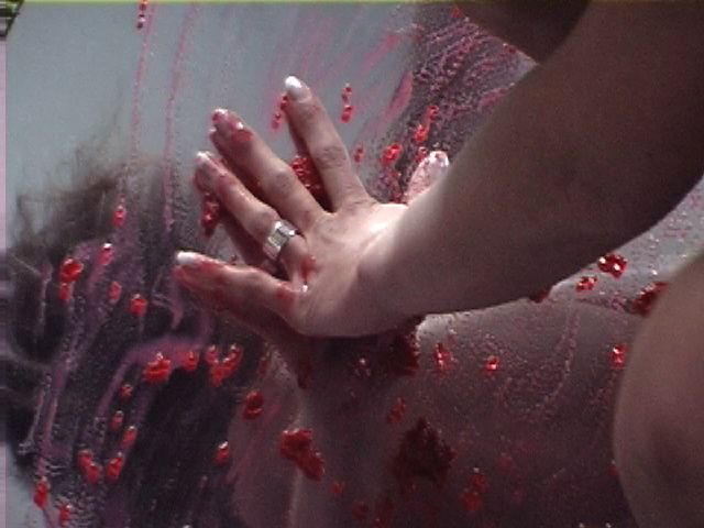 a hand rubbing raspberries onto a mirror